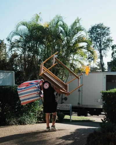 Relocation Rangers mover carrying chair to moving truck
